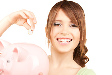 Image showing lovely teenage girl with piggy bank and coin