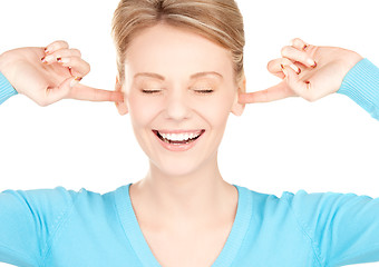 Image showing smiling woman with hands over ears