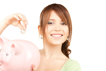 Image showing lovely teenage girl with piggy bank and coin