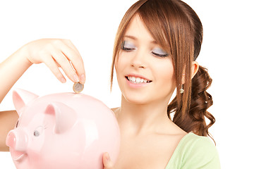 Image showing lovely teenage girl with piggy bank and coin