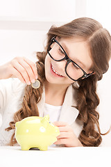 Image showing little girl with piggy bank and coin