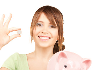 Image showing lovely teenage girl with piggy bank and coin