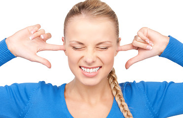 Image showing smiling woman with fingers in ears