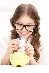 Image showing little girl with piggy bank and money