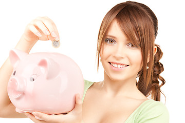 Image showing lovely teenage girl with piggy bank and coin