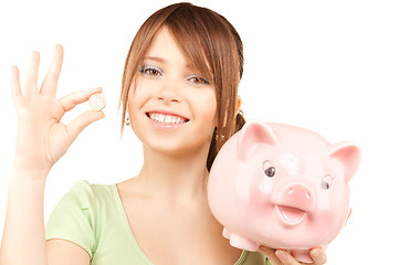 Image showing lovely teenage girl with piggy bank and coin