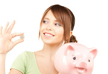 Image showing lovely teenage girl with piggy bank and coin