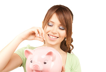 Image showing lovely teenage girl with piggy bank and coin