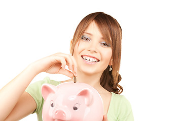 Image showing lovely teenage girl with piggy bank and coin