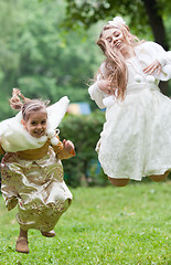 Image showing Two little beautiful girls jumping in a park