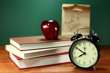 Image showing Lunch, Apple, Books and Clock on Desk at School
