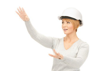 Image showing female contractor in helmet working with something imaginary