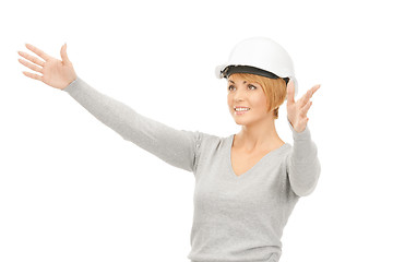 Image showing female contractor in helmet working with something imaginary