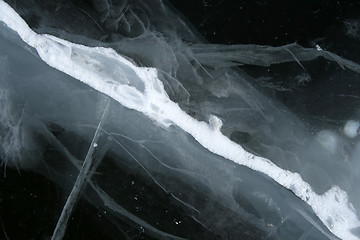 Image showing Cracked snowy ice, deep black water