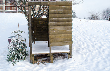 Image showing beach changing booth full of snow and small tree  