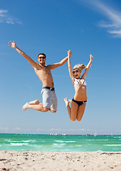 Image showing happy couple jumping on the beach