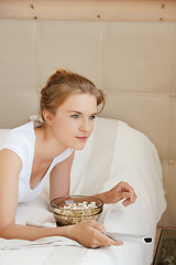 Image showing happy teenage girl with TV remote and popcorn