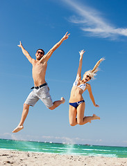 Image showing happy couple jumping on the beach