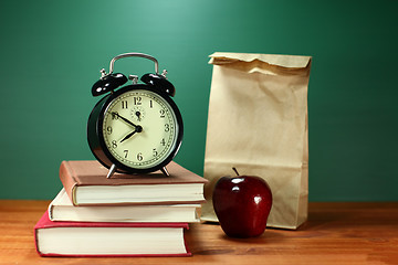 Image showing Lunch, Apple, Books and Clock on Desk at School