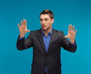 Image showing man in suit working with something imaginary