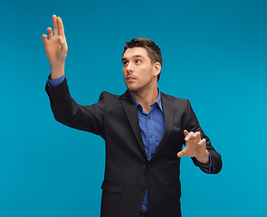 Image showing man in suit working with something imaginary