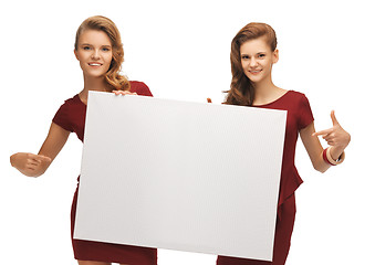 Image showing two teenage girls in red dresses with blank board