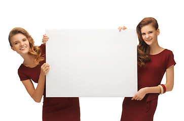 Image showing two teenage girls in red dresses with blank board