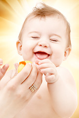 Image showing laughing baby boy in mother hands with rubber duck