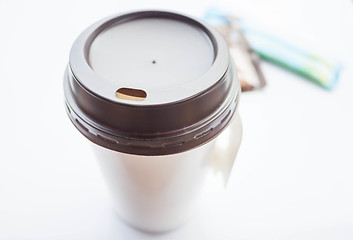 Image showing Hot coffee in paper cup with sugar packs on white background