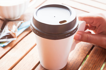 Image showing Hot coffee in paper cup serving on wood table