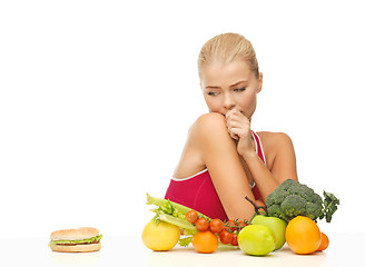 Image showing doubting woman with fruits and hamburger
