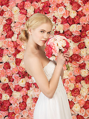 Image showing woman with bouquet and background full of roses