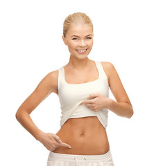 Image showing beautiful sporty woman pointing at her abs