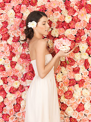 Image showing woman with bouquet and background full of roses