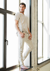 Image showing handsome man standing on the windowsill