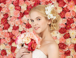 Image showing woman with bouquet and background full of roses