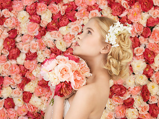 Image showing woman with bouquet and background full of roses