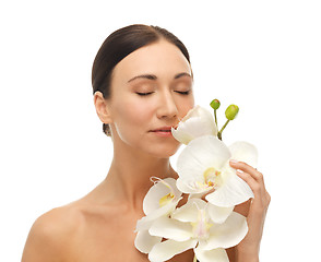 Image showing woman smelling white orchid flower