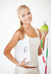 Image showing sporty woman with scale, apple and measuring tape