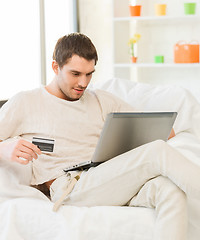 Image showing young man with laptop and credit card at home