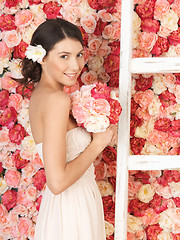 Image showing woman with bouquet and background full of roses