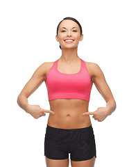 Image showing beautiful sporty woman pointing at her six pack