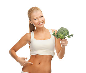 Image showing woman pointing at her abs and holding broccoli