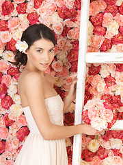 Image showing woman with bouquet and background full of roses