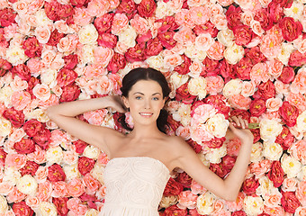 Image showing woman with bouquet and background full of roses