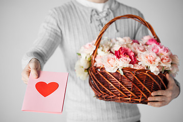 Image showing man holding basket full of flowers and postcard