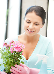 Image showing woman holding pot with flower and spray bottle