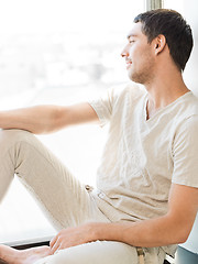 Image showing man in casual clothes sitting on the windowsill