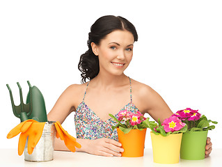 Image showing housewife with flower in pot and gardening set