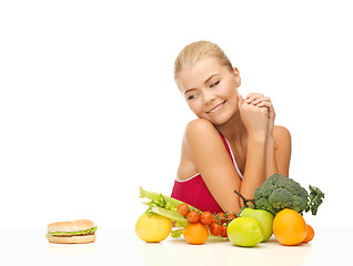 Image showing doubting woman with fruits and hamburger